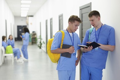 Photo of Medical student in uniforms with backpacks and notebooks at university, selective focus