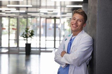 Photo of Medical student in uniform with backpack indoors, space for text