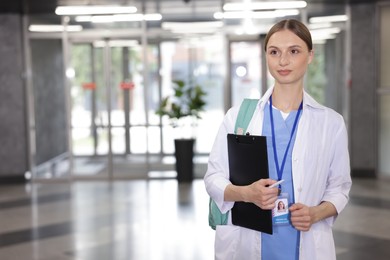 Photo of Medical student in uniform with backpack and clipboard indoors, space for text