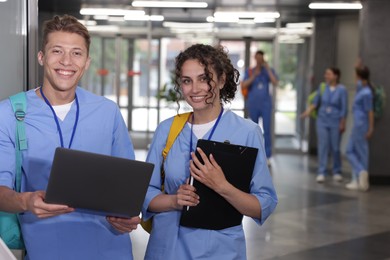 Photo of Medical students in uniforms with laptop indoors, selective focus