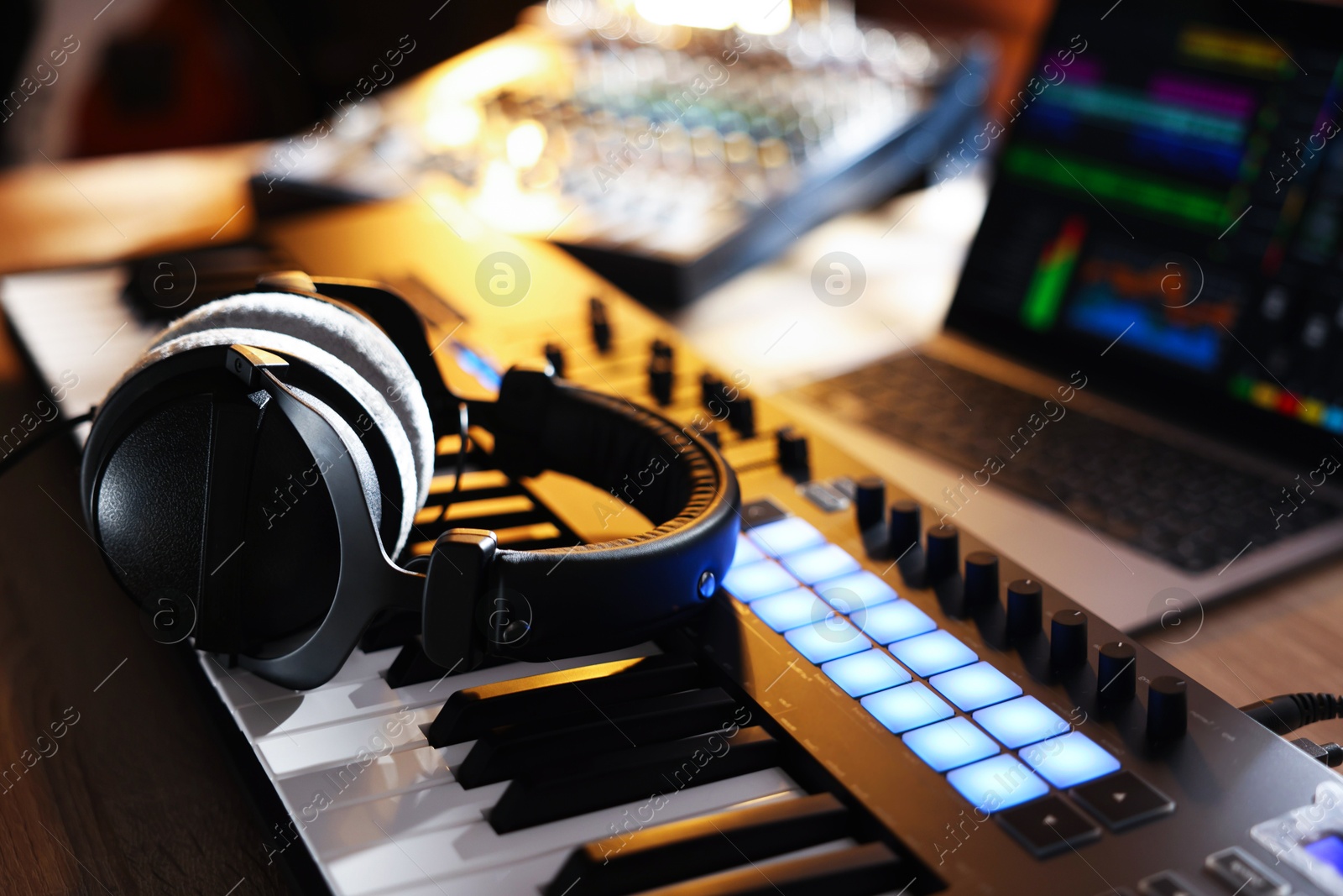 MIDI keyboard with headphones, laptop and dj mixer on wooden table indoors, closeup Photo of MIDI keyboard with headphones, laptop and dj mixer on wooden table indoors, closeup