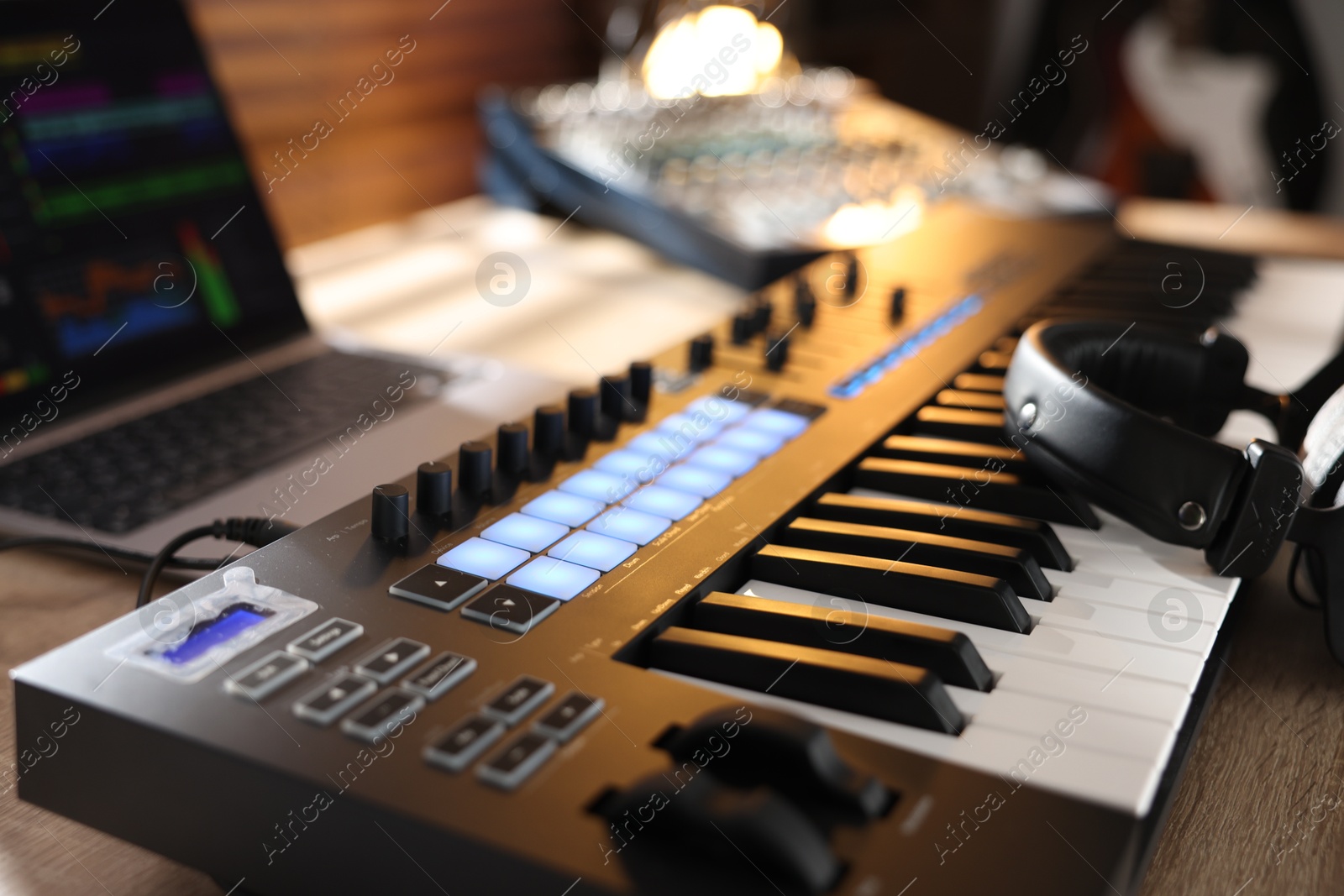MIDI keyboard with headphones, laptop and dj mixer on wooden table indoors, closeup Photo of MIDI keyboard with headphones, laptop and dj mixer on wooden table indoors, closeup