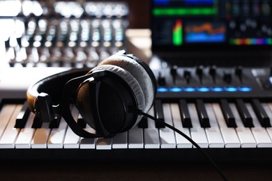 Photo of MIDI keyboard with headphones, dj mixer and laptop on table, closeup
