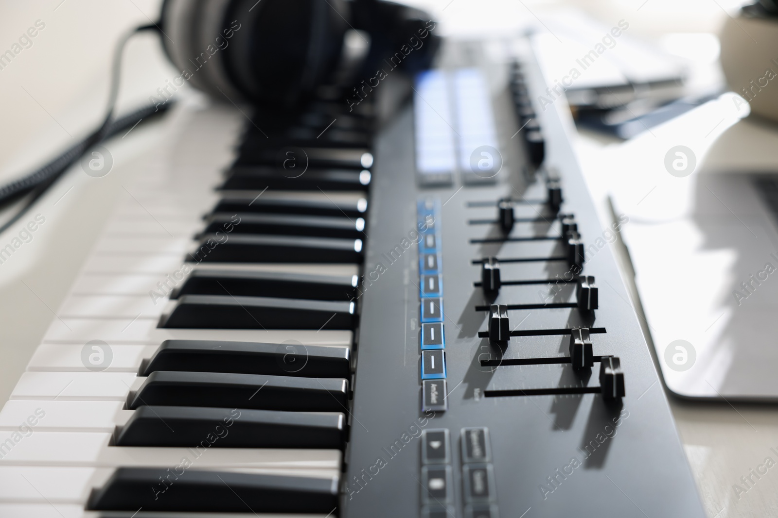 Photo of MIDI keyboard and headphones on table, closeup