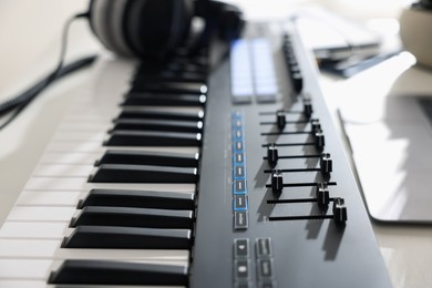 Photo of MIDI keyboard and headphones on table, closeup