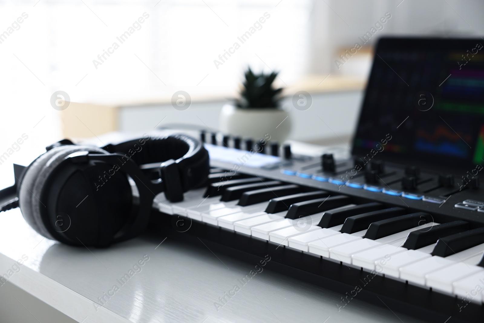 MIDI keyboard, headphones and laptop on white wooden table indoors, closeup Photo of MIDI keyboard, headphones and laptop on white wooden table indoors, closeup