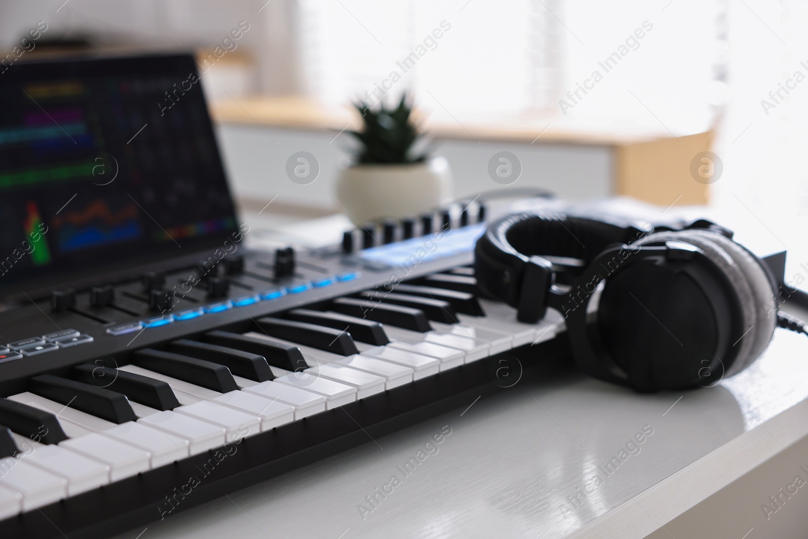 MIDI keyboard, headphones and laptop on white wooden table indoors, closeup Photo of MIDI keyboard, headphones and laptop on white wooden table indoors, closeup