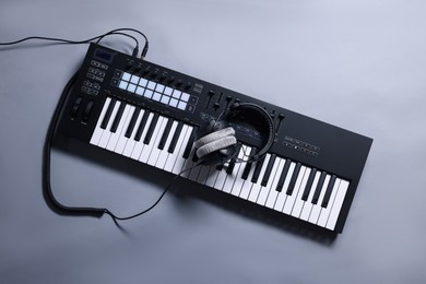 Photo of MIDI keyboard with headphones on grey background, top view