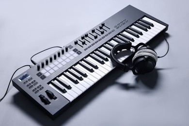 Photo of MIDI keyboard with headphones on grey background, above view