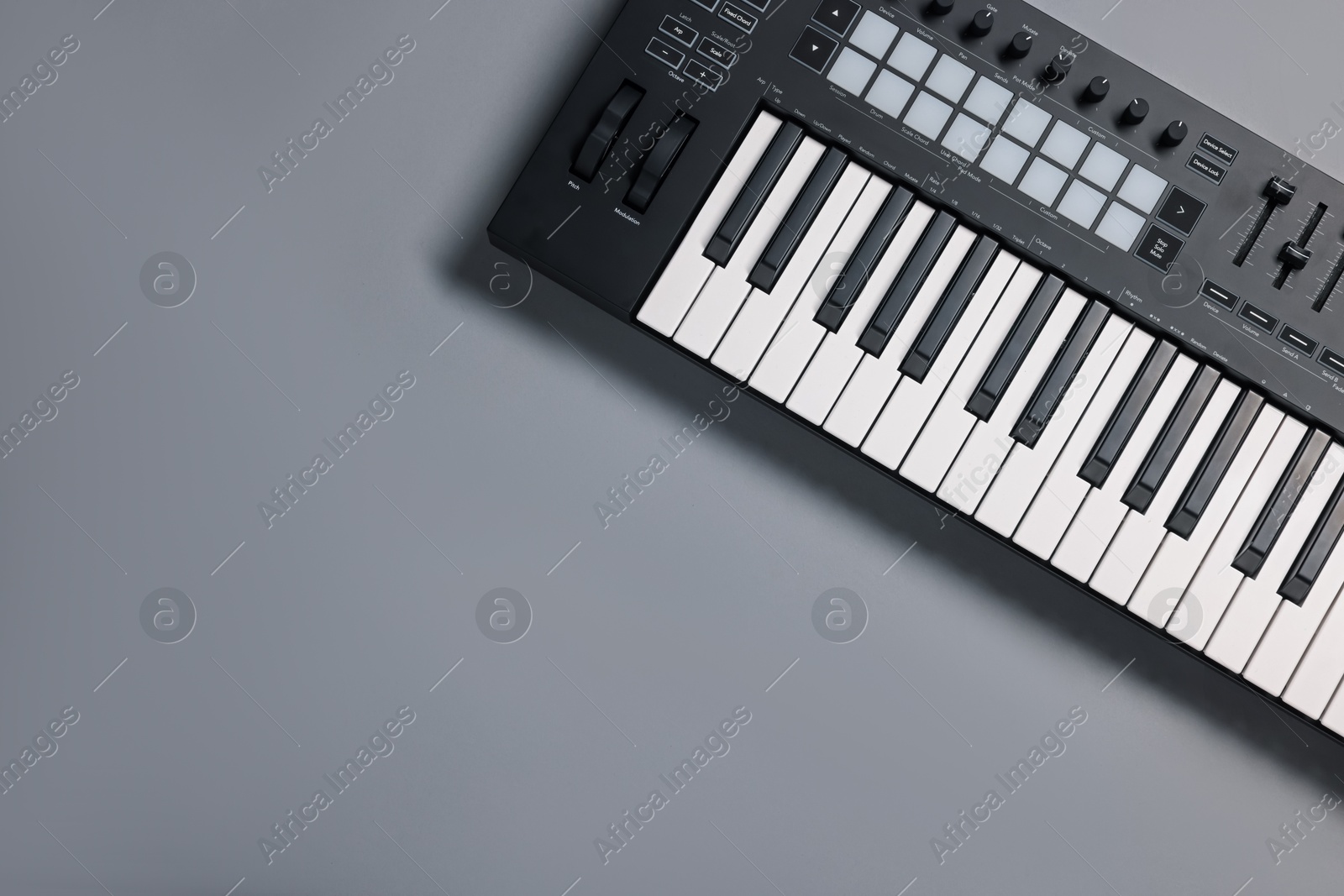 Photo of One portable MIDI keyboard on grey background, top view. Space for text