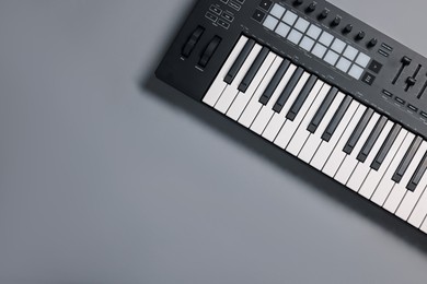Photo of One portable MIDI keyboard on grey background, top view. Space for text
