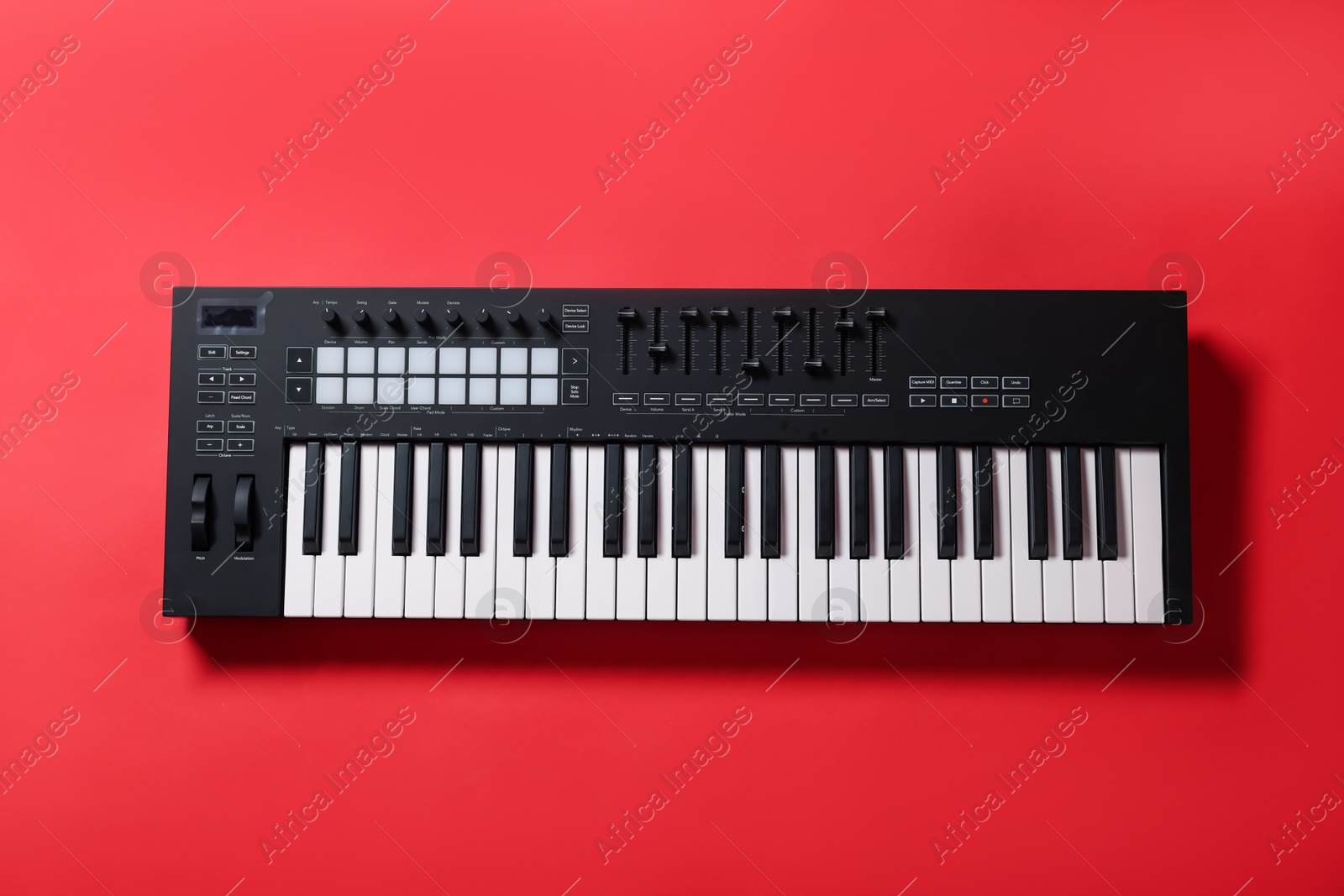 One portable MIDI keyboard on red background, top view Photo of One portable MIDI keyboard on red background, top view