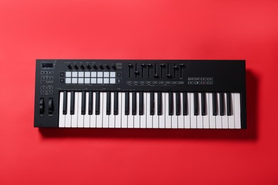 Photo of One portable MIDI keyboard on red background, top view