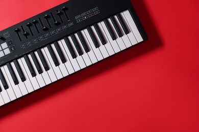 Photo of One portable MIDI keyboard on red background, top view. Space for text