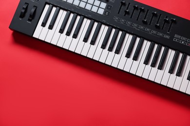 Photo of One portable MIDI keyboard on red background, top view. Space for text