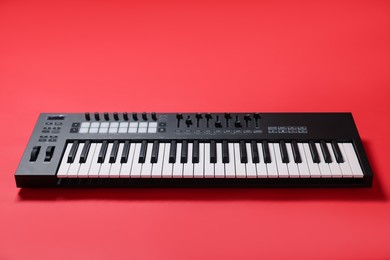 Photo of One portable MIDI keyboard on red background, above view