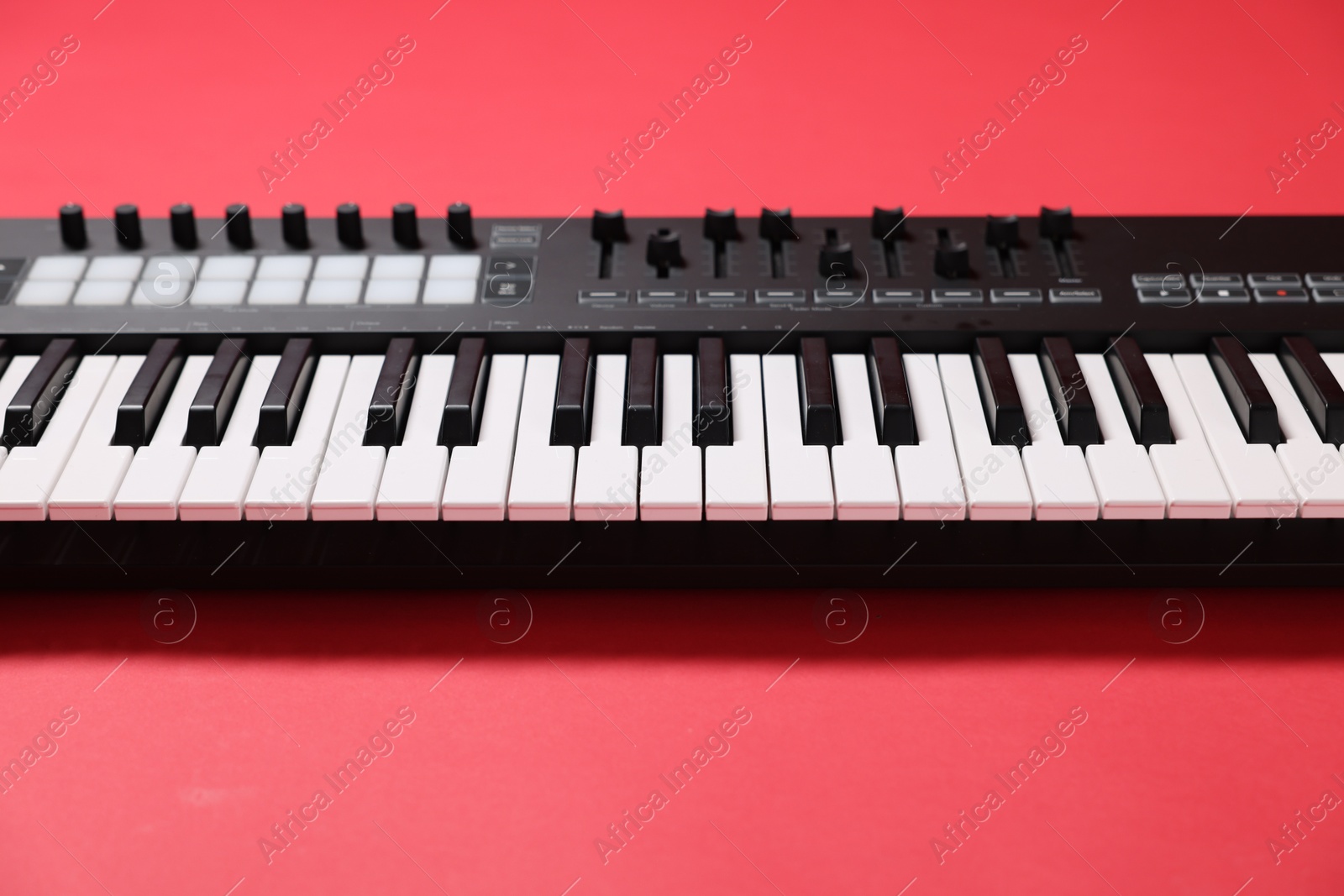 Photo of One portable MIDI keyboard on red background, closeup