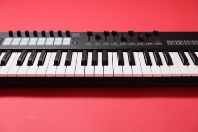 Photo of One portable MIDI keyboard on red background, closeup