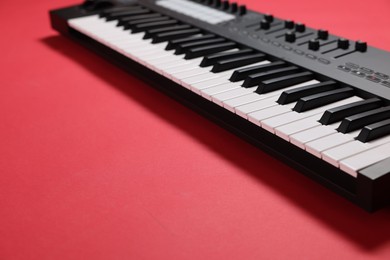 Photo of One portable MIDI keyboard on red background, closeup. Space for text