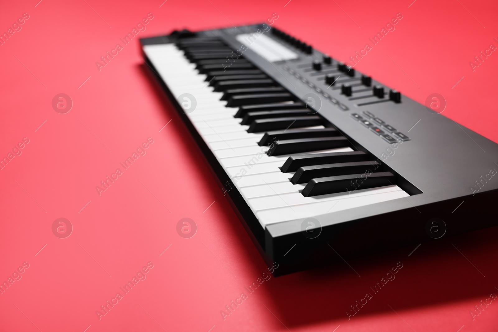 Photo of One portable MIDI keyboard on red background, closeup. Space for text