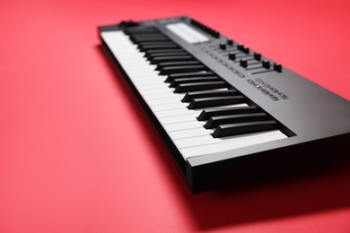 Photo of One portable MIDI keyboard on red background, closeup. Space for text