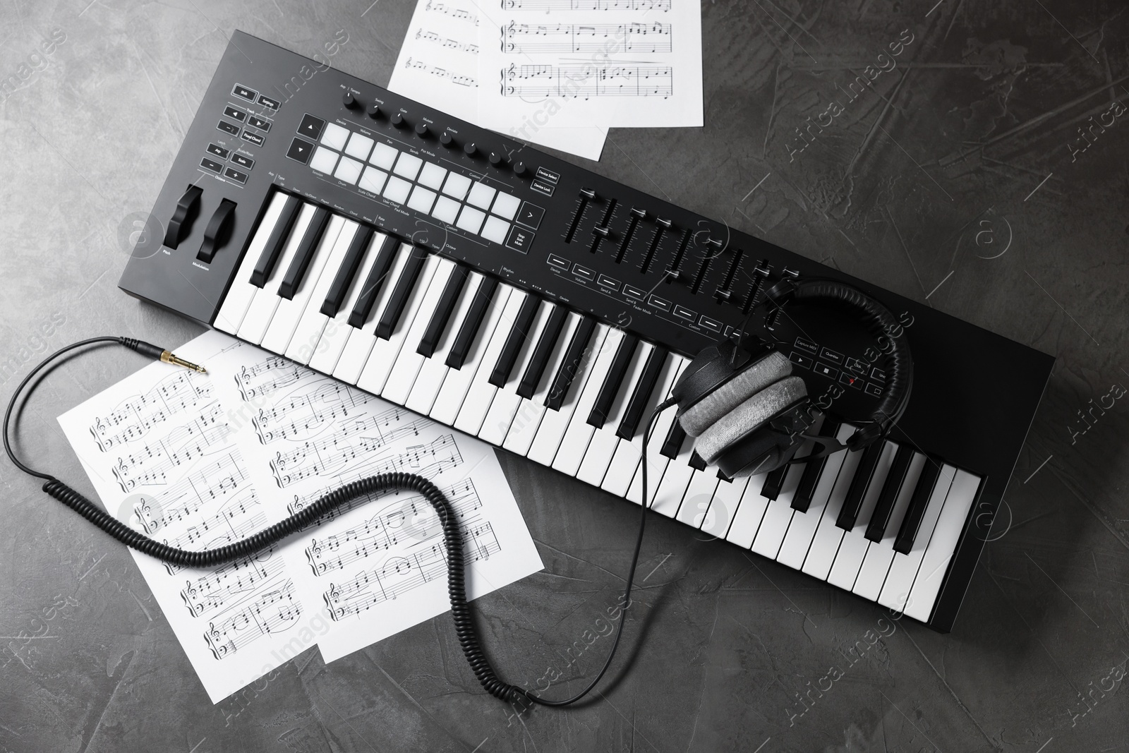 MIDI keyboard, headphones and music sheets on grey table, flat lay Photo of MIDI keyboard, headphones and music sheets on grey table, flat lay
