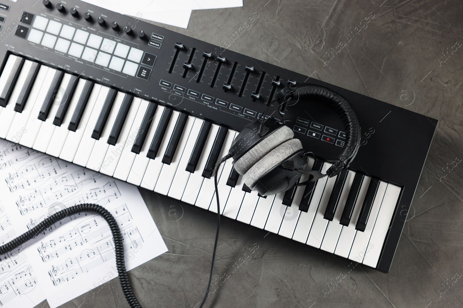 MIDI keyboard, headphones and music sheets on grey table, flat lay Photo of MIDI keyboard, headphones and music sheets on grey table, flat lay