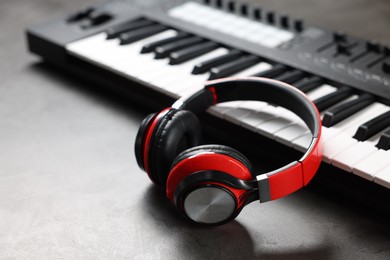 Photo of MIDI keyboard and headphones on grey table, closeup. Space for text