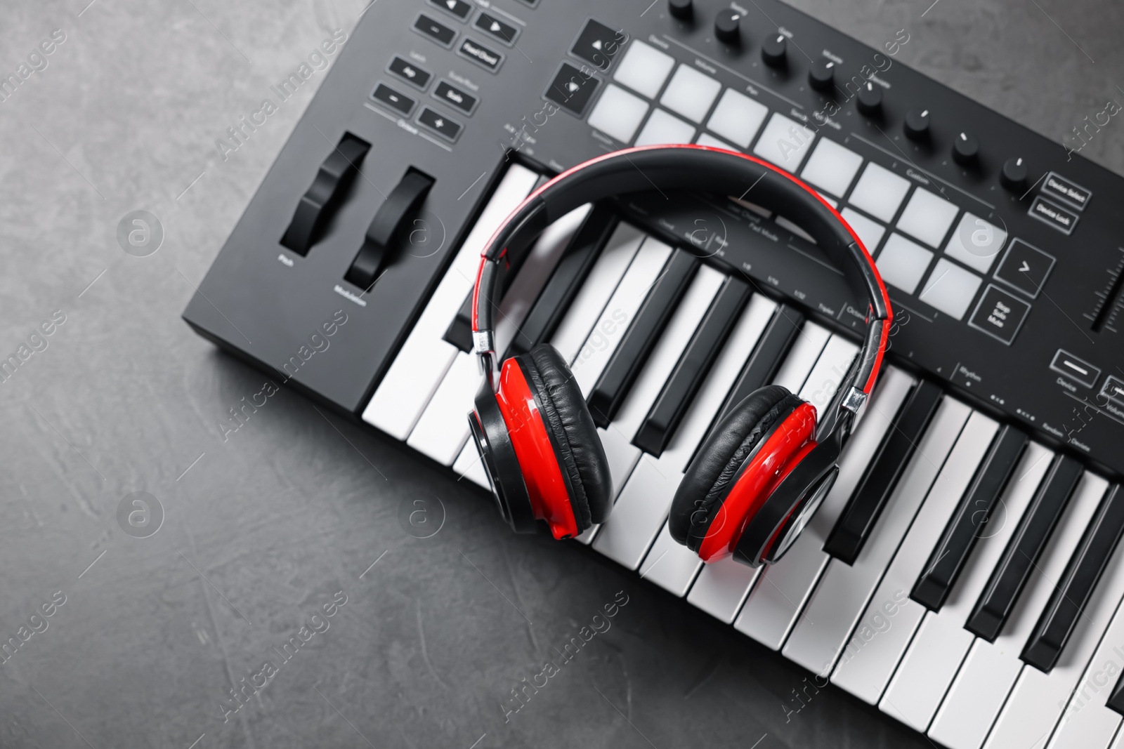Photo of MIDI keyboard and headphones on grey table, top view