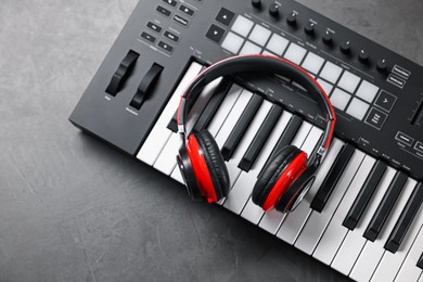 Photo of MIDI keyboard and headphones on grey table, top view