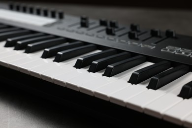 Photo of One portable MIDI keyboard on grey table, closeup