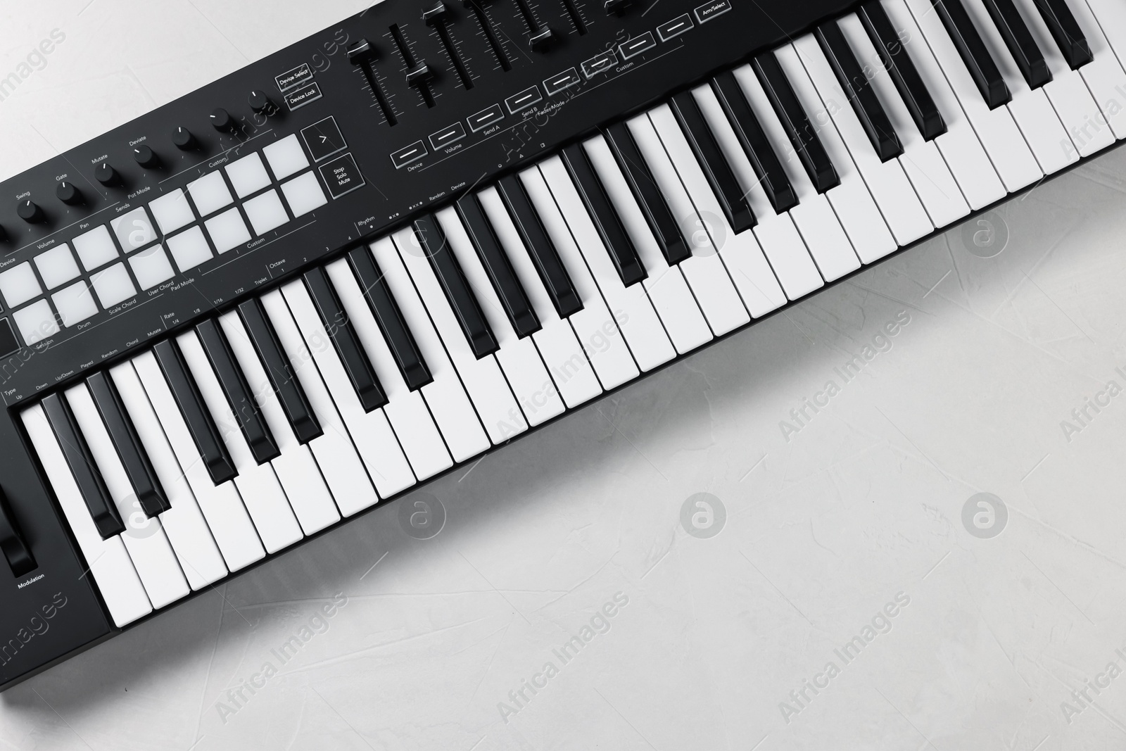 Photo of One portable MIDI keyboard on white table, top view. Space for text