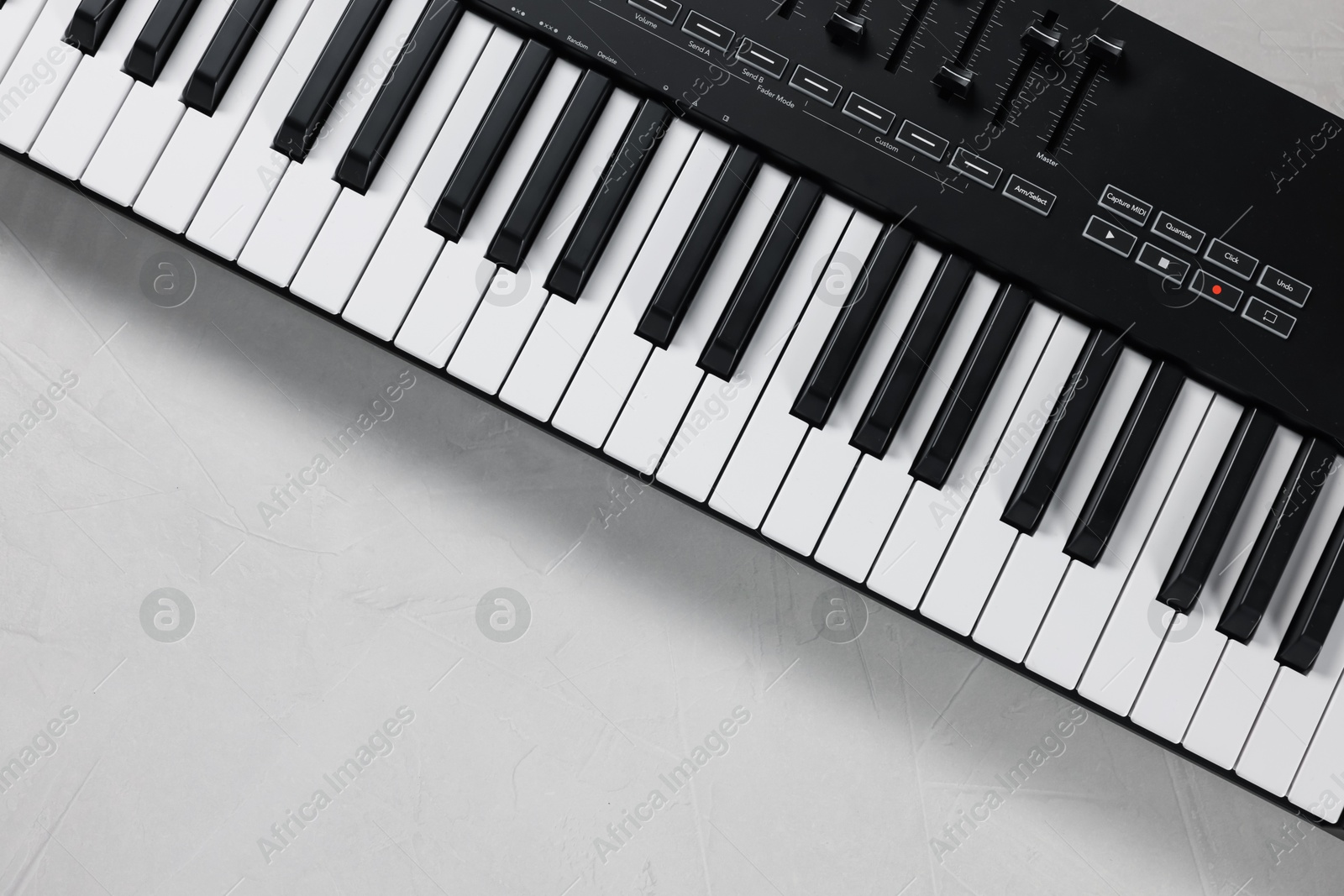 One portable MIDI keyboard on white table, top view. Space for text Photo of One portable MIDI keyboard on white table, top view. Space for text