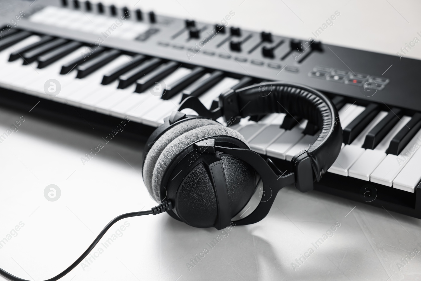 MIDI keyboard with headphones on white table, closeup Photo of MIDI keyboard with headphones on white table, closeup