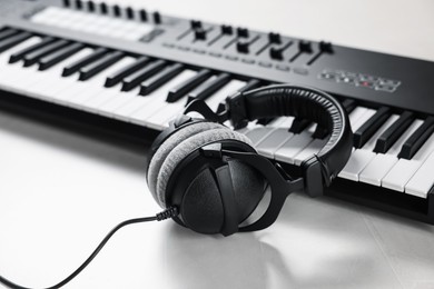 Photo of MIDI keyboard with headphones on white table, closeup