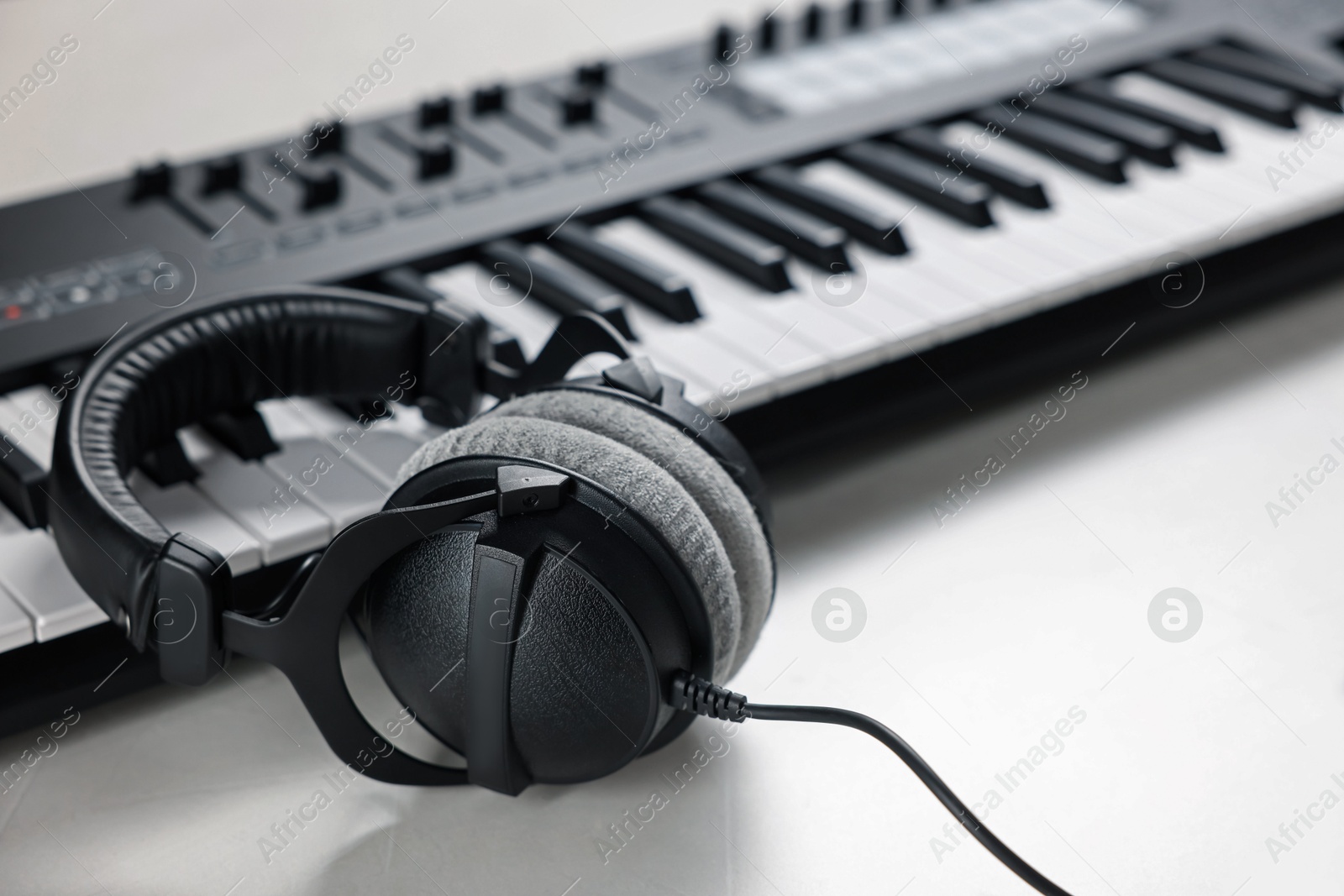 MIDI keyboard with headphones on white table, closeup Photo of MIDI keyboard with headphones on white table, closeup