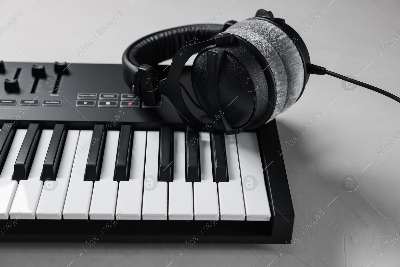 Photo of MIDI keyboard with headphones on white table, closeup