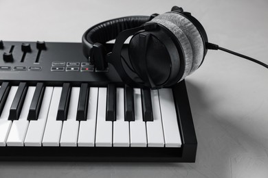 Photo of MIDI keyboard with headphones on white table, closeup