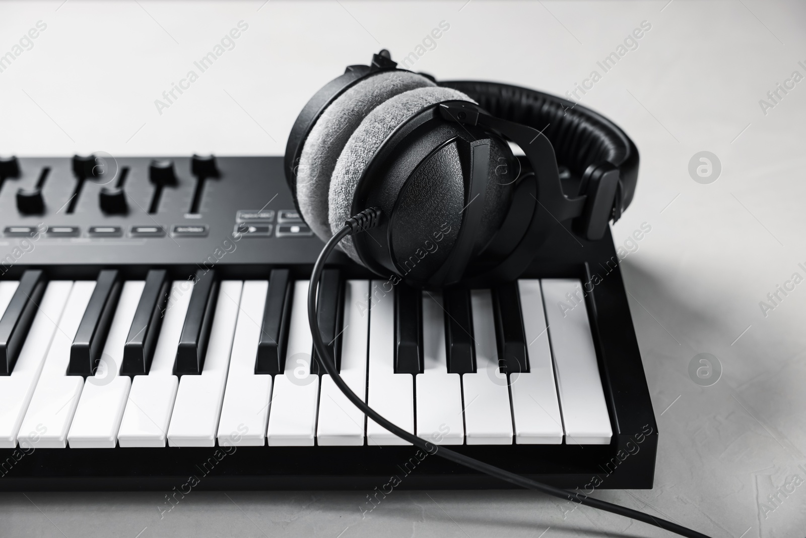 MIDI keyboard with headphones on white table, closeup Photo of MIDI keyboard with headphones on white table, closeup