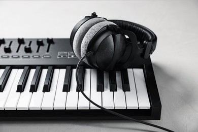 Photo of MIDI keyboard with headphones on white table, closeup