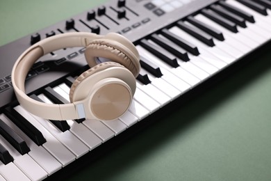 Photo of MIDI keyboard and headphones on green background, closeup