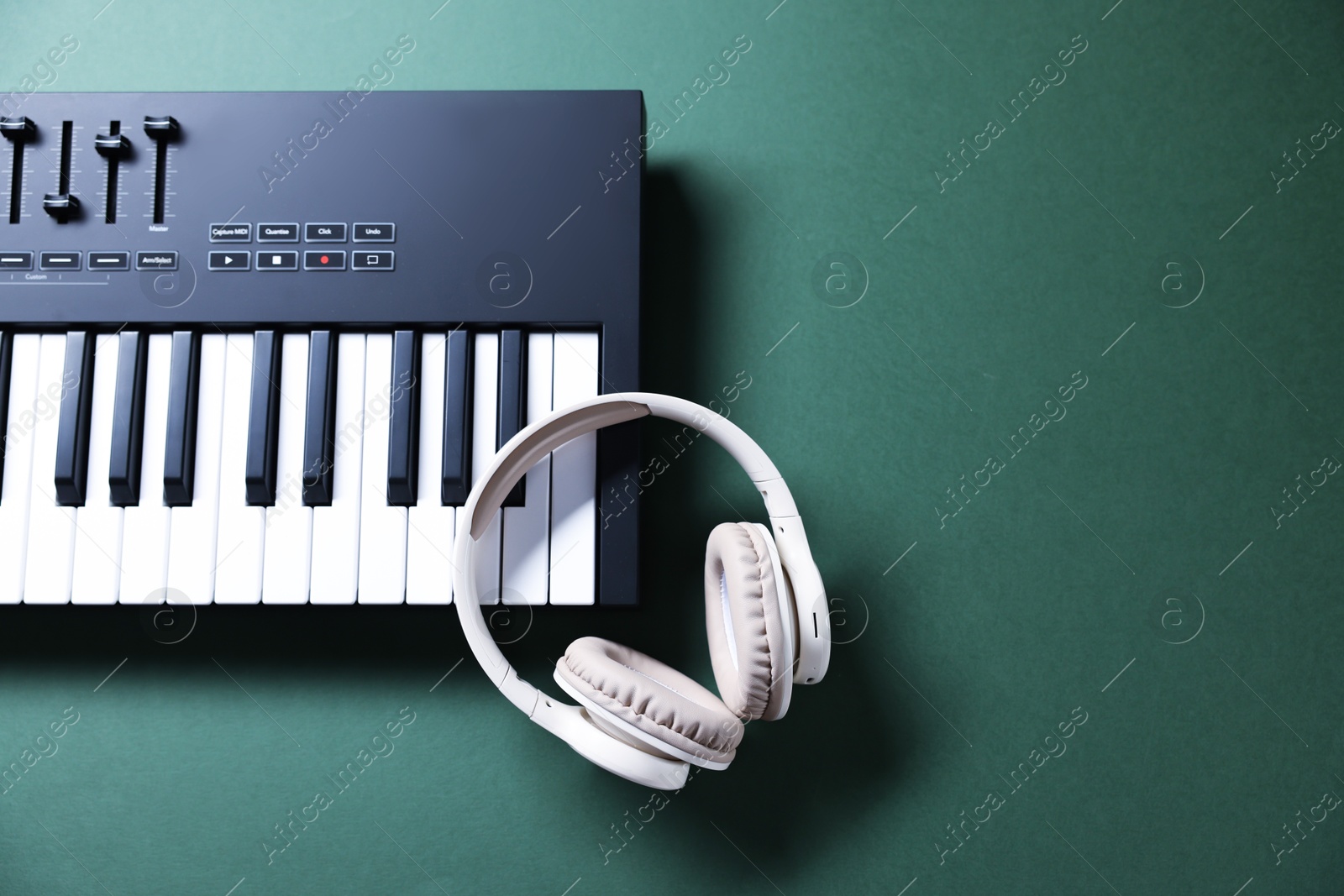 MIDI keyboard and headphones on green background, top view. Space for text Photo of MIDI keyboard and headphones on green background, top view. Space for text