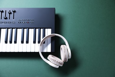 Photo of MIDI keyboard and headphones on green background, top view. Space for text