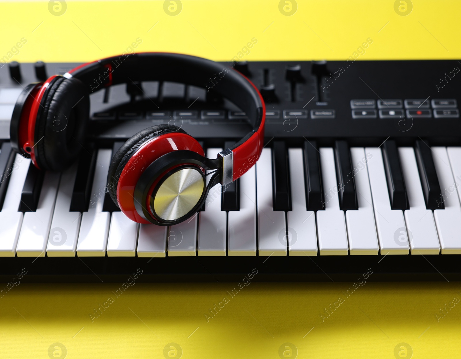 MIDI keyboard with headphones on yellow background, closeup Photo of MIDI keyboard with headphones on yellow background, closeup