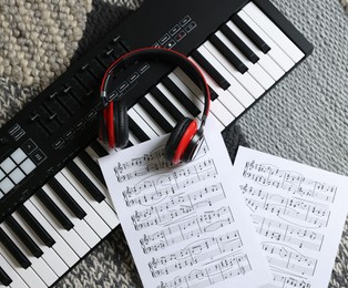 Photo of MIDI keyboard, music sheets and headphones on carpet, flat lay