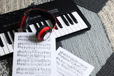 Photo of MIDI keyboard, music sheets and headphones on carpet, above view