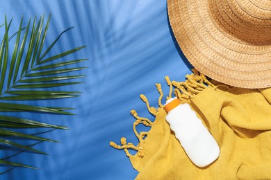 Photo of Beach accessories and palm leaf on blue background, flat lay. Space for text