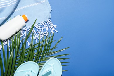 Photo of Beach accessories and palm leaves on blue background, flat lay. Space for text