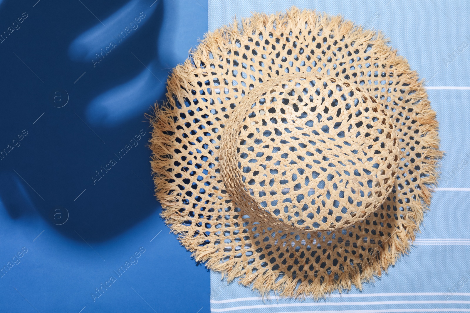 Wicker hat and beach towel on blue background, top view. Space for text Photo of Wicker hat and beach towel on blue background, top view. Space for text