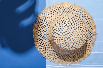 Photo of Wicker hat and beach towel on blue background, top view. Space for text